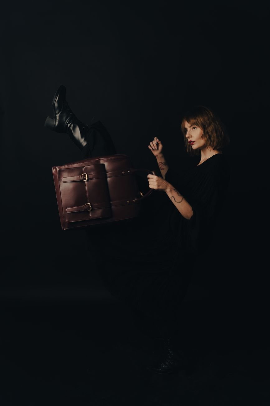 Woman posing with a designer leather handbag against a dark studio background