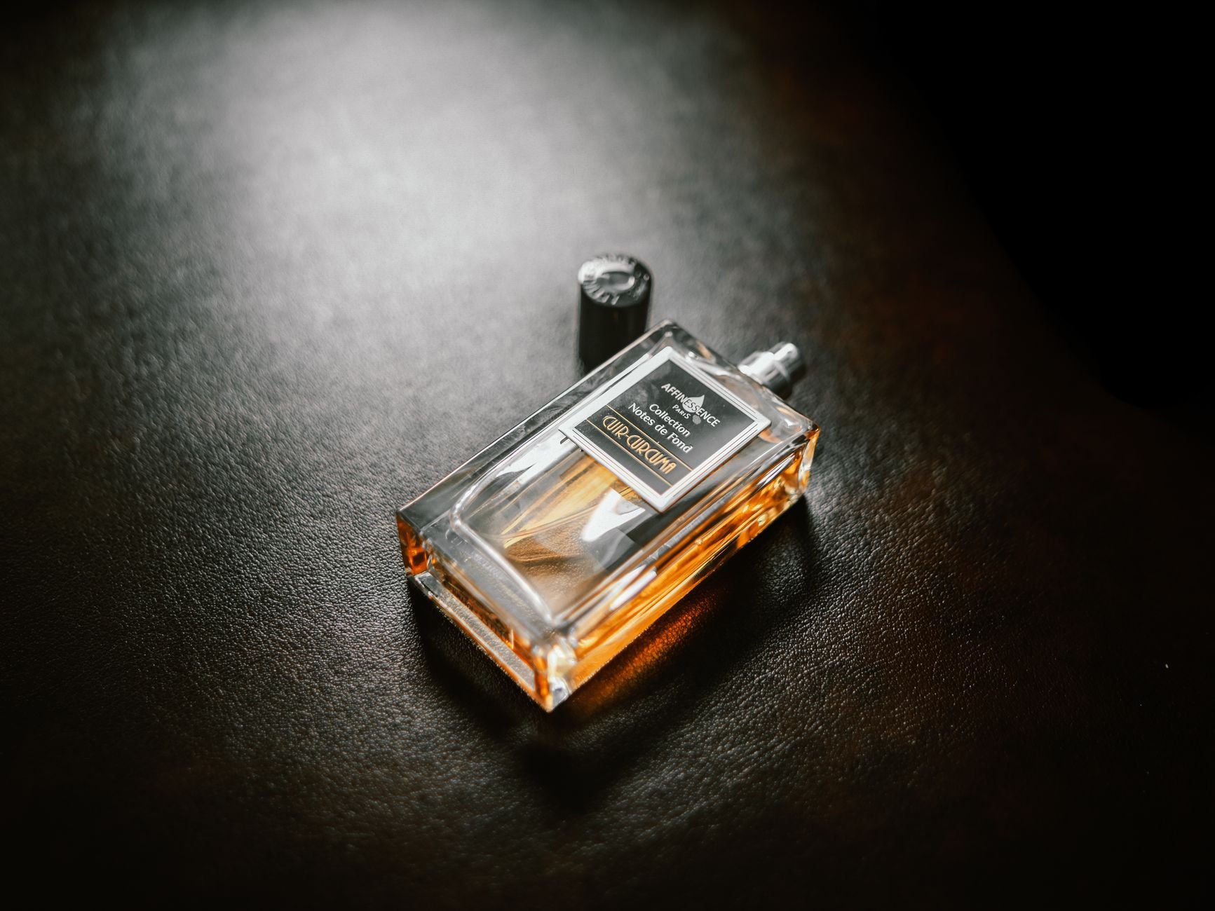 Luxurious perfume bottle illuminated against a dark background — premium products delivered worldwide